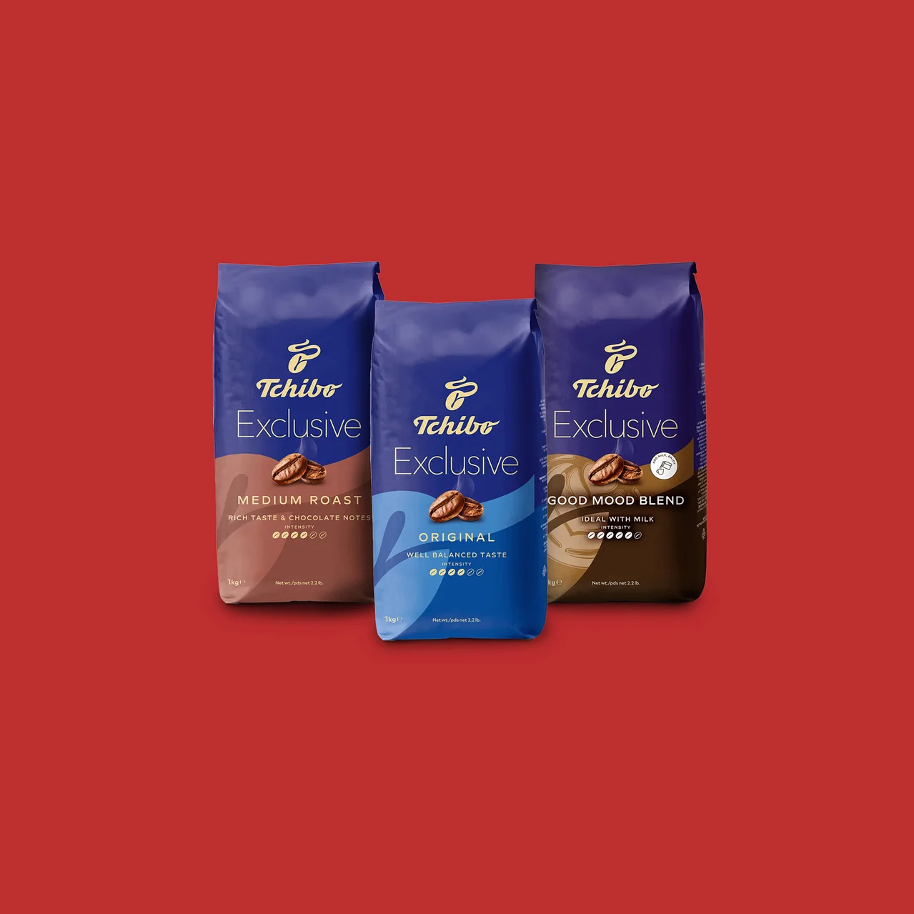 Három kék Tchibo Exclusive kávécsomag áll piros háttér előtt. Balról jobbra: Medium Roast barna aljjal, Original világoskék aljjal és Good Mood Blend sötétbarna aljjal.