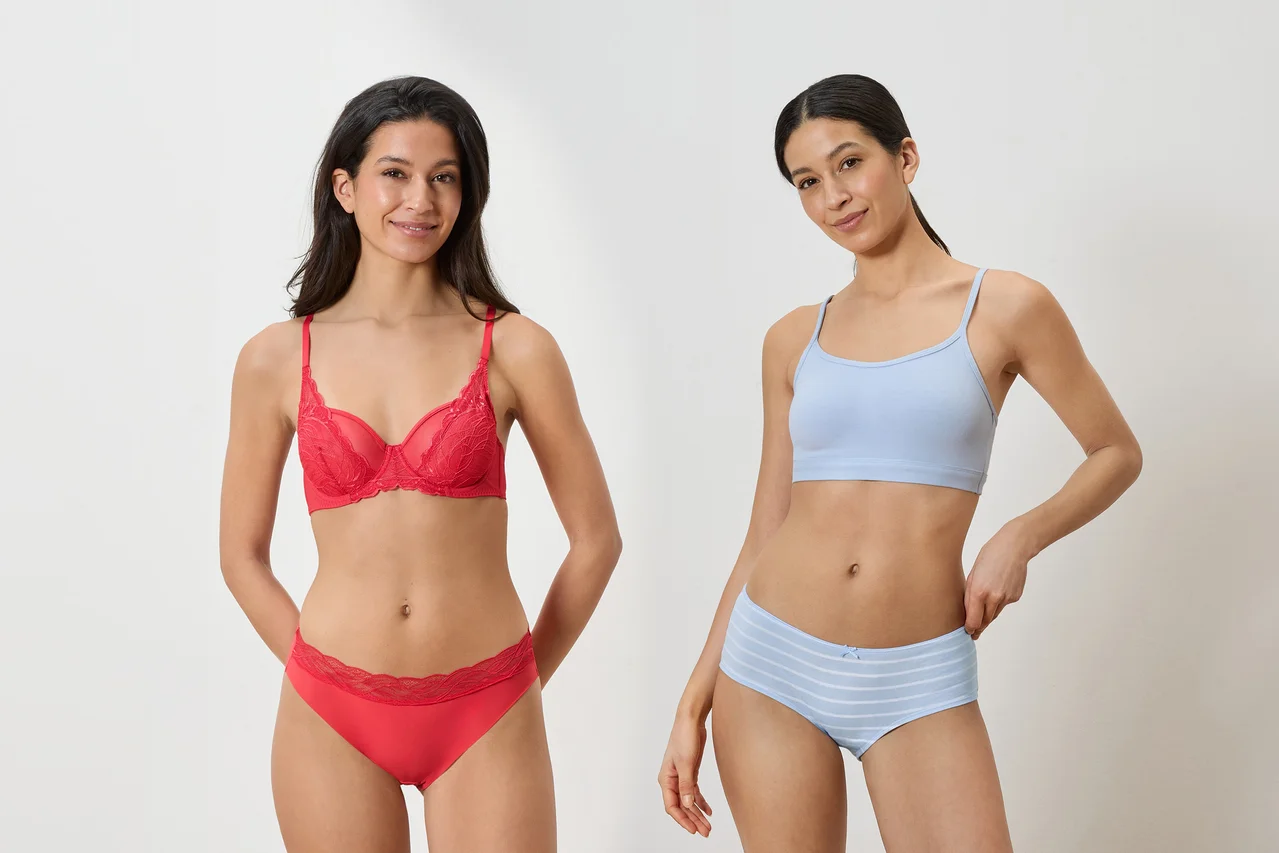 Két nő áll egymás mellett. A bal oldali nő piros csipkés melltartót és hozzá illő piros csipkés alsóneműt visel. A jobb oldali nő világoskék bralette-et és világoskék csíkos rövidnadrágot visel.
