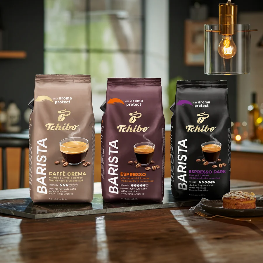 Három csomag Tchibo Barista kávébab áll az asztalon, balról jobbra: Caffè Crema, Espresso és Espresso Dark.