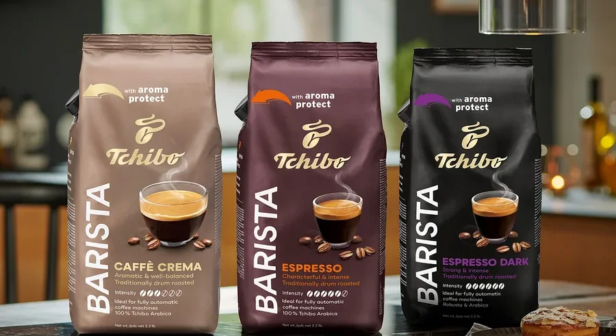 Három csomag Tchibo Barista kávébab áll az asztalon, balról jobbra: Caffè Crema, Espresso és Espresso Dark.