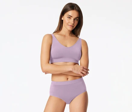 Világoslila bralette-et és hozzá illő alsónadrágot viselő nő, karba tett kézzel, előre néz.