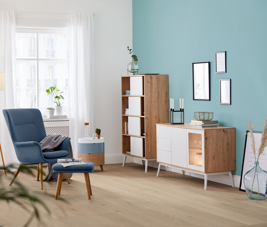 Nappali belső kék fotellel, lámpával és kerek dohányzóasztallal, emeletes.