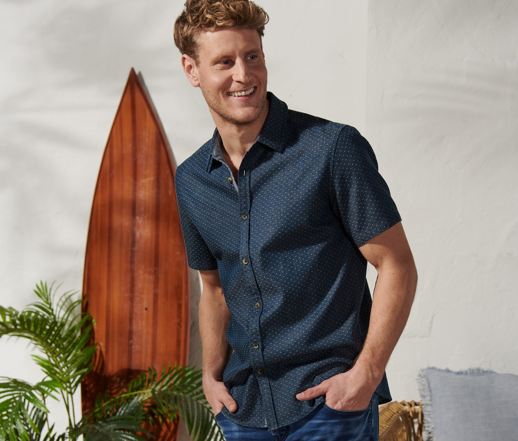 Férfi a zsebében a kezével pózol egy »Mustang« rövid ujjú ingben és farmer rövidnadrágban.