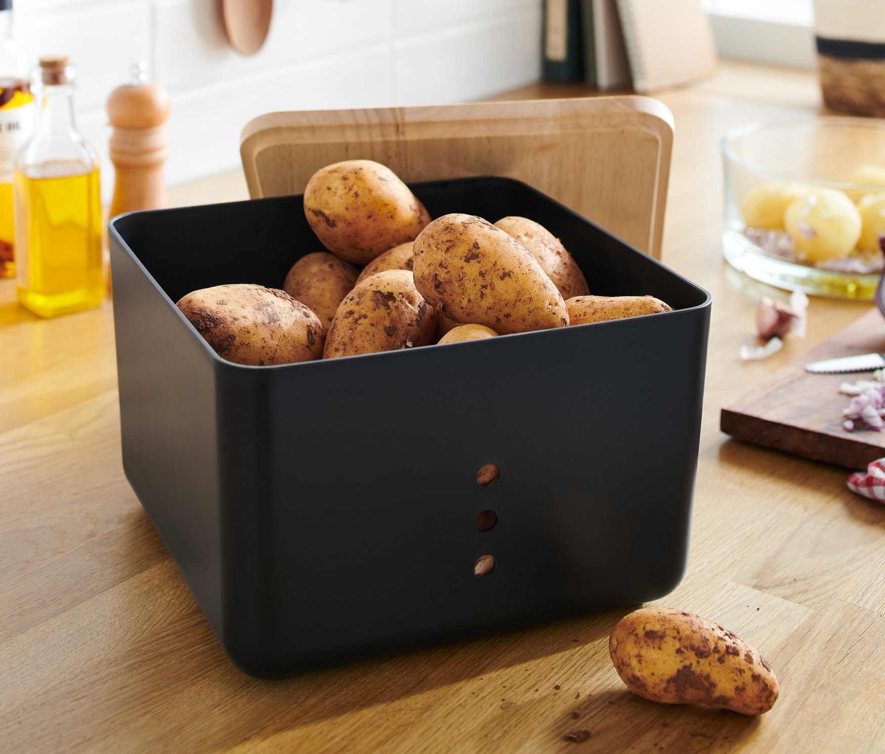 Burgonya a fekete zöldségtároló dobozban, fa fedéllel.