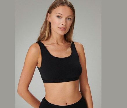 Hosszú szőke hajú nő visel egy fekete SCHIESSER bustier melltartót, előre nézve.