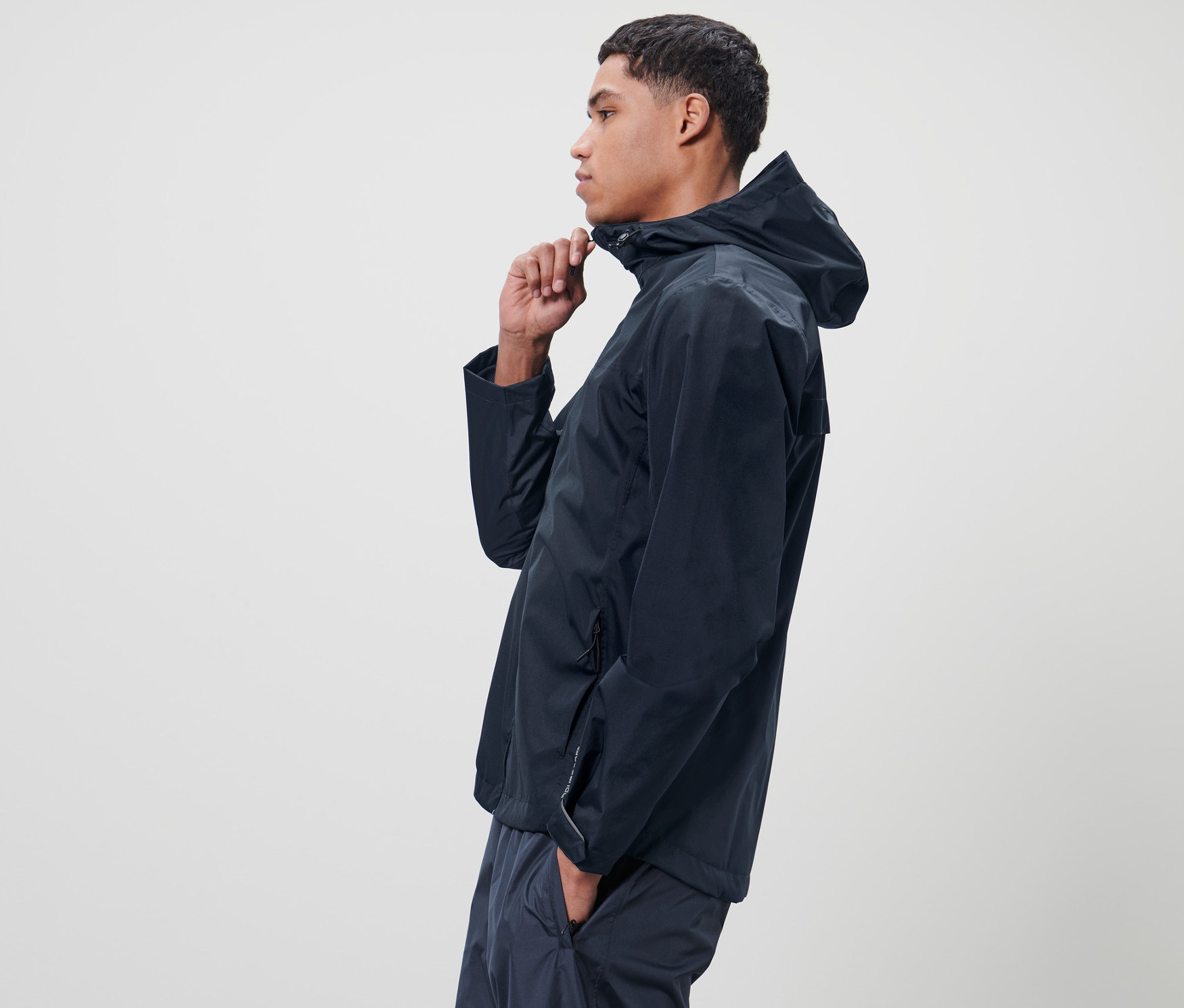 Férfi cipzározza a kék, unisex esőkabátot.