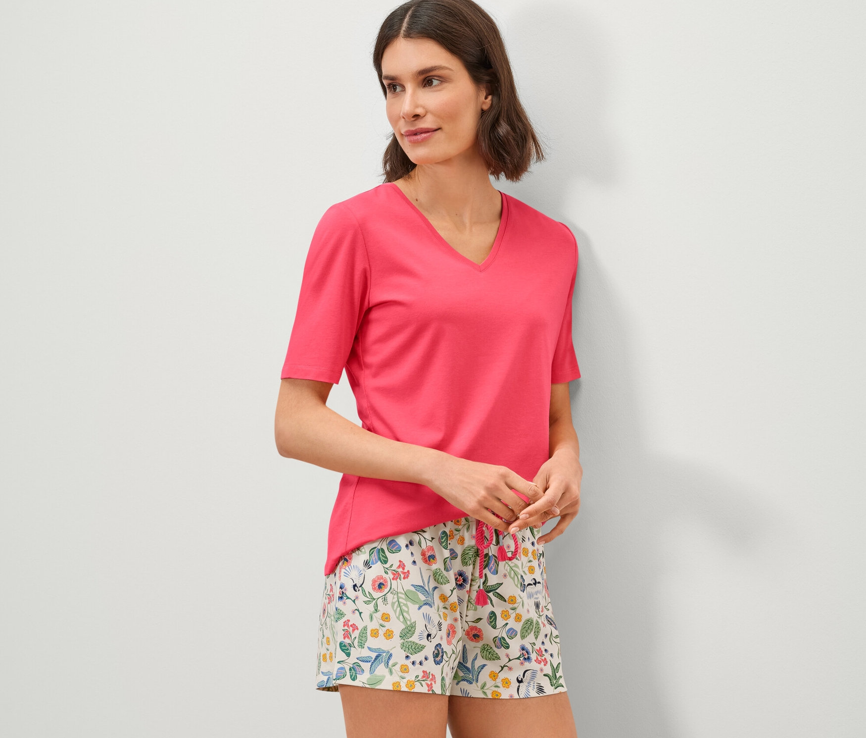 Nő virágos rövidnadrágos pizsamát visel.