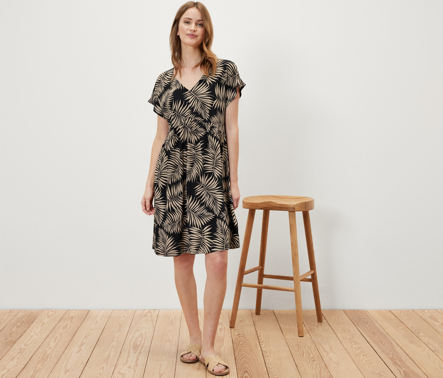 Egy nő áll, és nyomott mintás jerseyruhát visel.