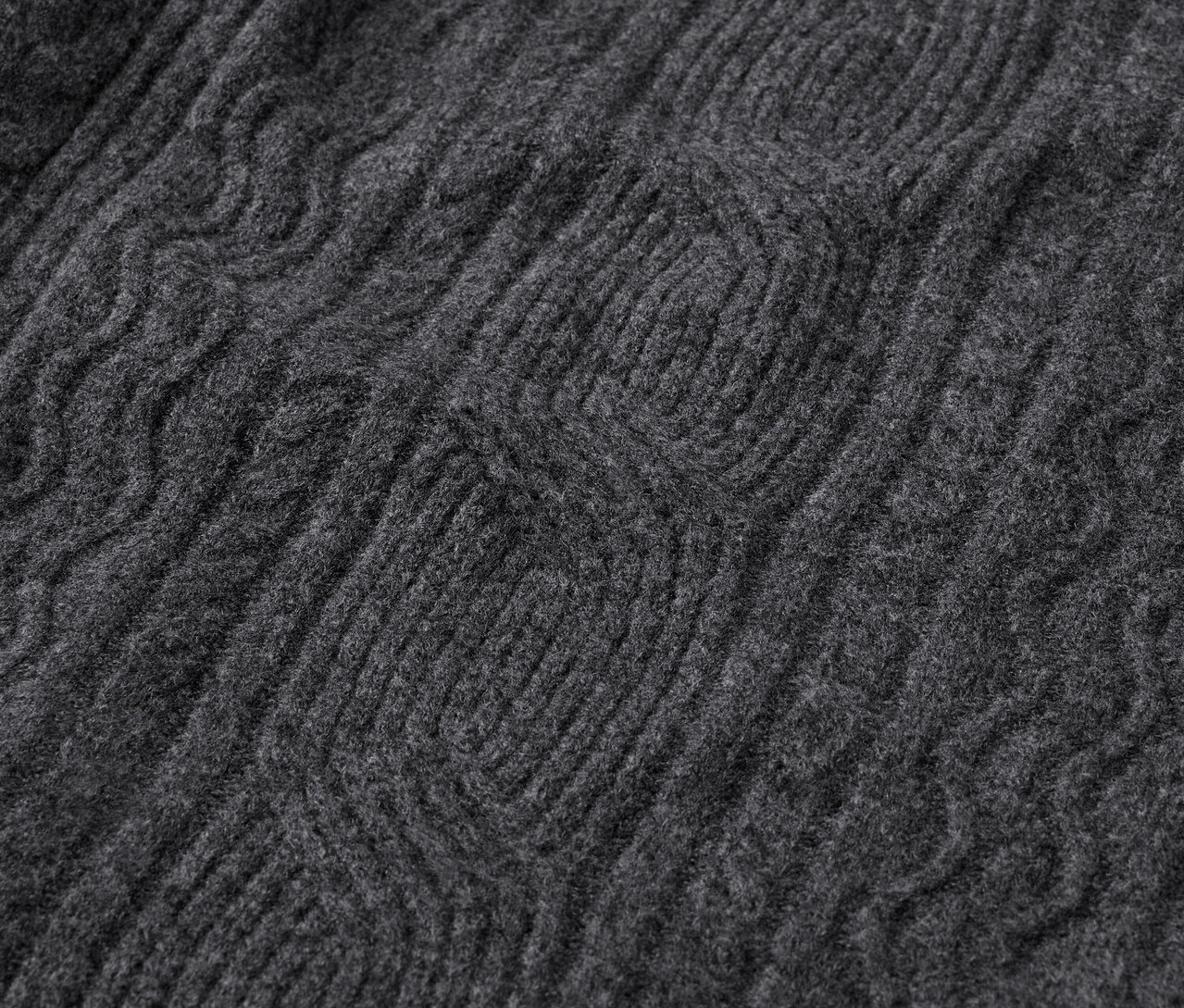 Egy szürke kötött pulóver kötésmintájának közeli képe.