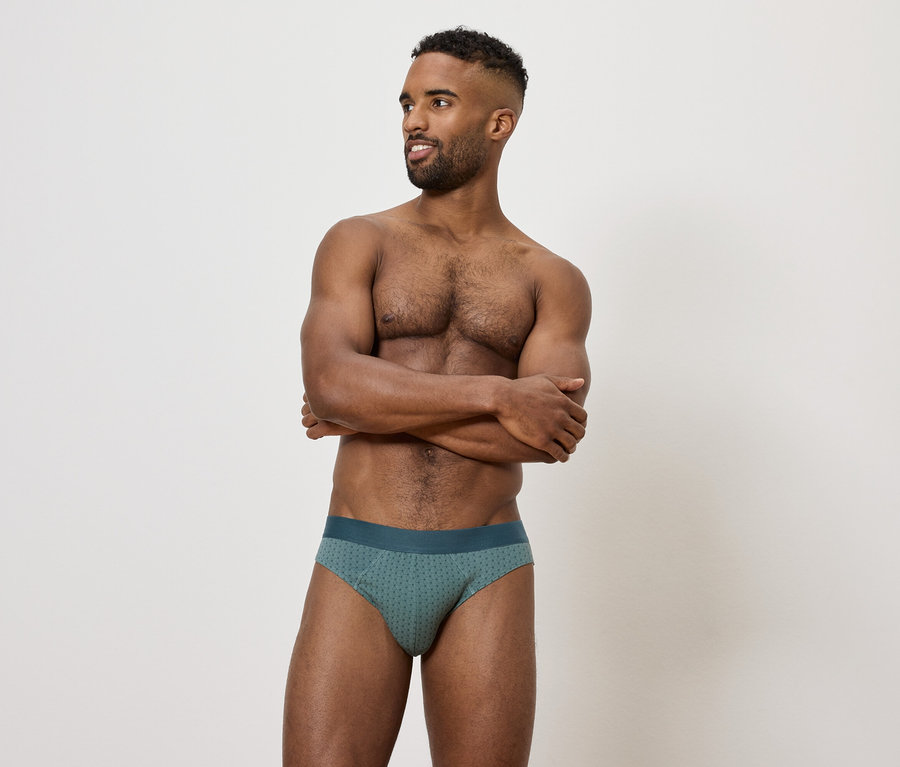 Férfi keresztbe tett karokkal a mellkasán, zöld alsónadrágot visel.