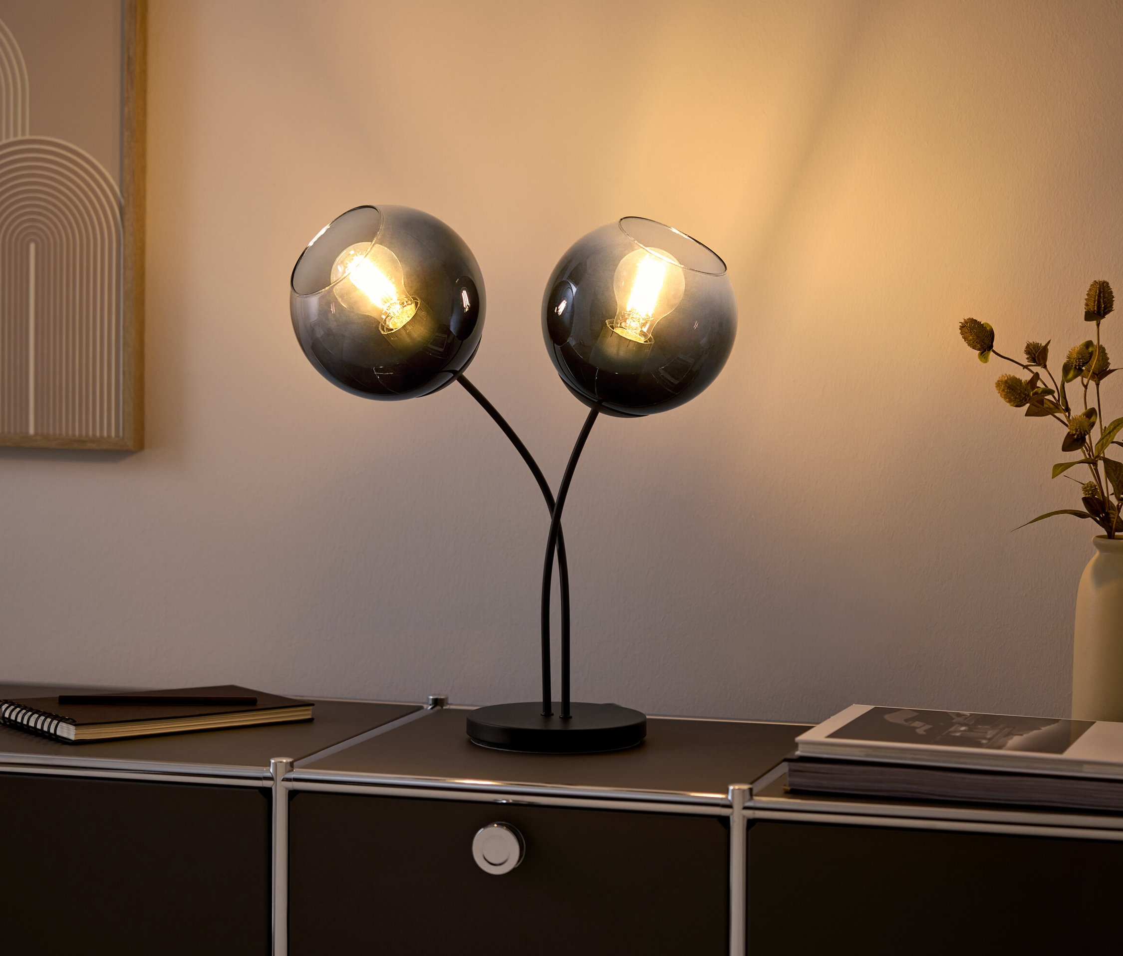 Két üveglámpa izzókkal egy fekete komódon.