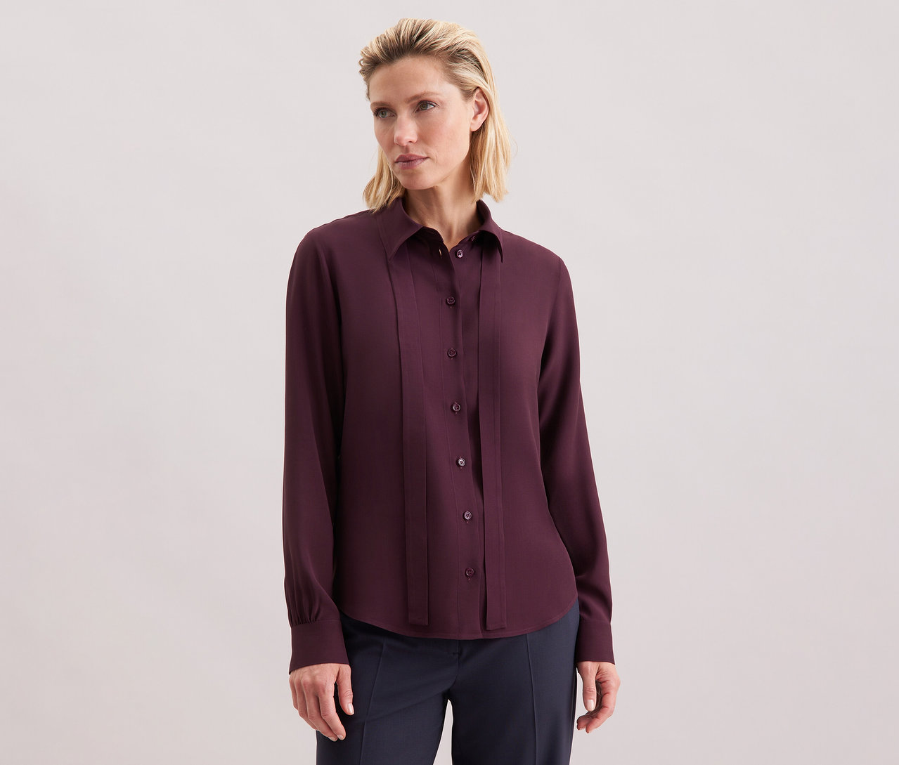 Nő visel egy Seidensticker sifon blúzt viszkózból, bordó színben, gombokkal.