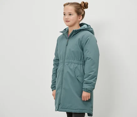 Egy lány oldalra állva visel egy zöld Kinder-Thermoparka termálparkát.
