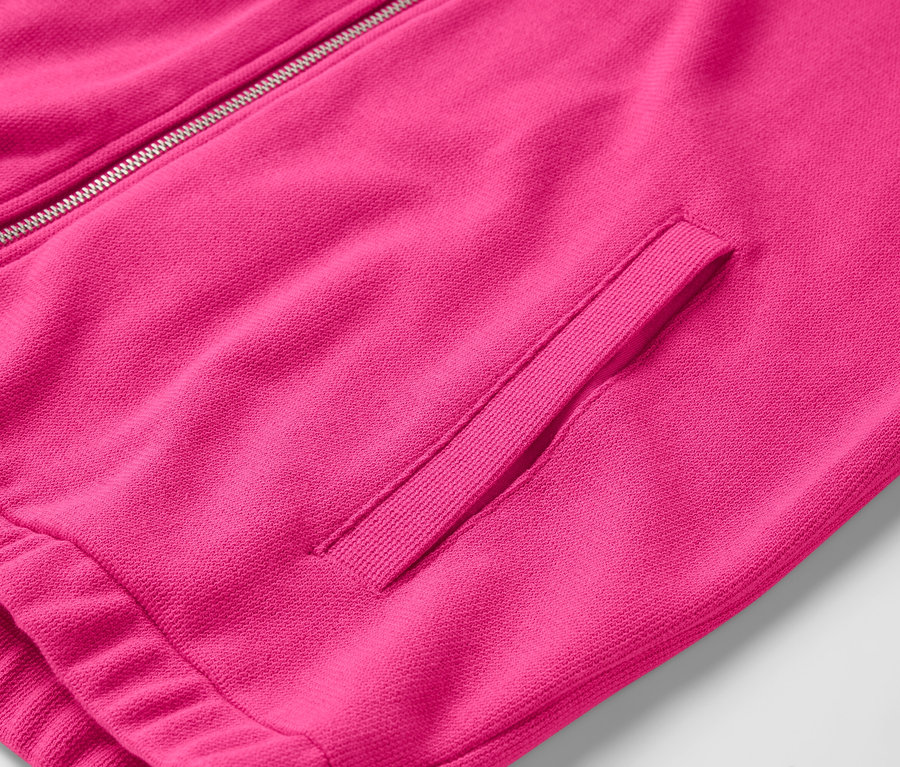 Egy rózsaszín cipzáras kabát részlete zsebbel.