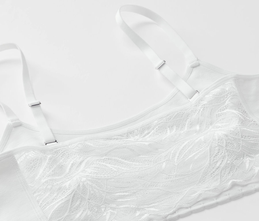 Egy fehér, csipkés, seamless bustier melltartó részlete.