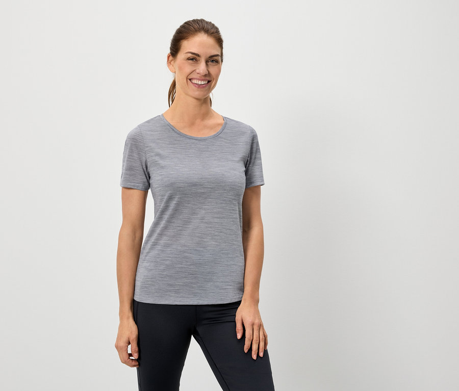 Nő visel egy szürke pólót és fekete leggingset.