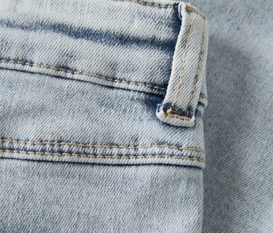 Kivilágosított kék farmer rózsaszín hímzett szívvel közelről.