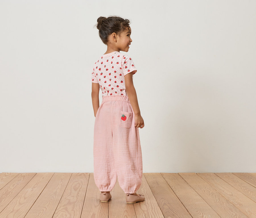 Kislány hátulról, eper mintás pólót és rózsaszín nadrágot visel eper részlettel.