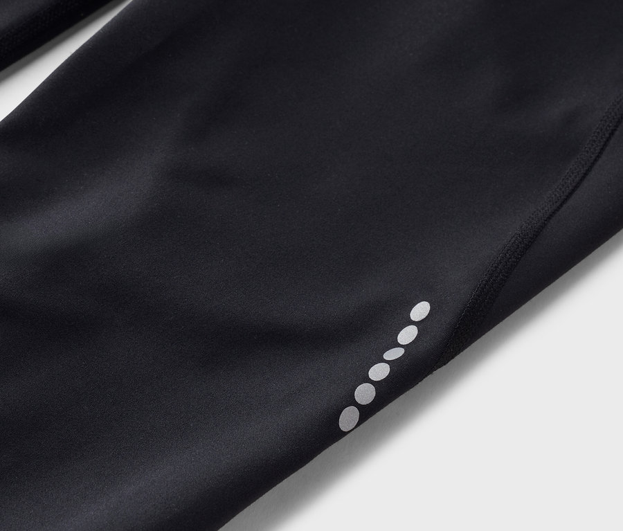 Közeli kép egy fekete leggingsről, melynek szárán fényvisszaverő pontok vannak.