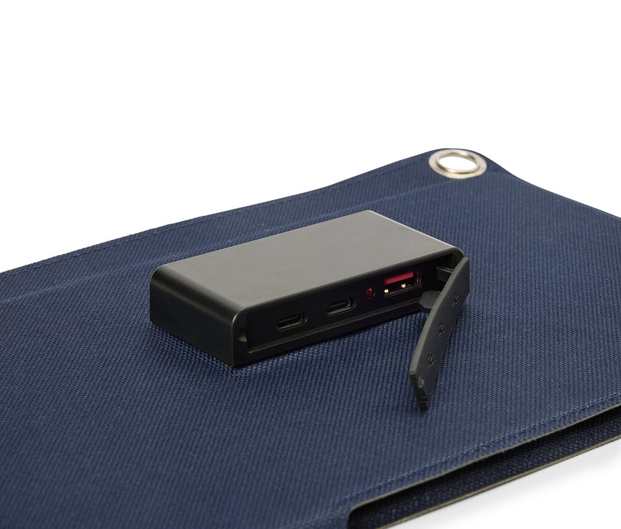 Fekete akkumulátor fekszik egy kék szövet felületen, látható USB porttal.
