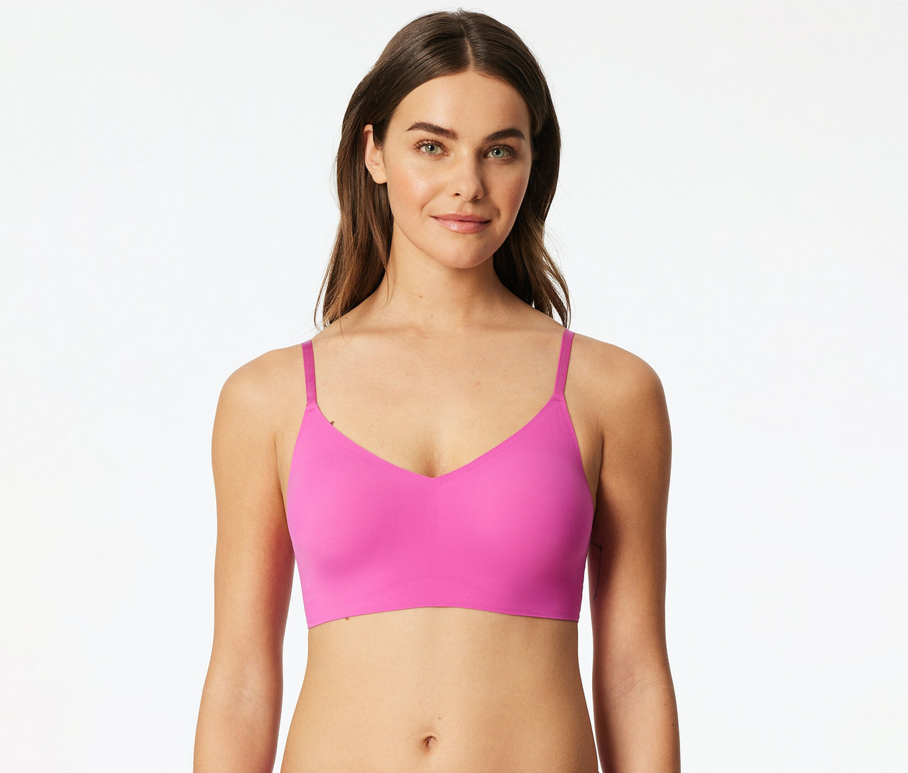 Egy nő rózsaszín SCHIESSER Invisible bustier melltartót visel betétekkel, és a kamerába mosolyog.