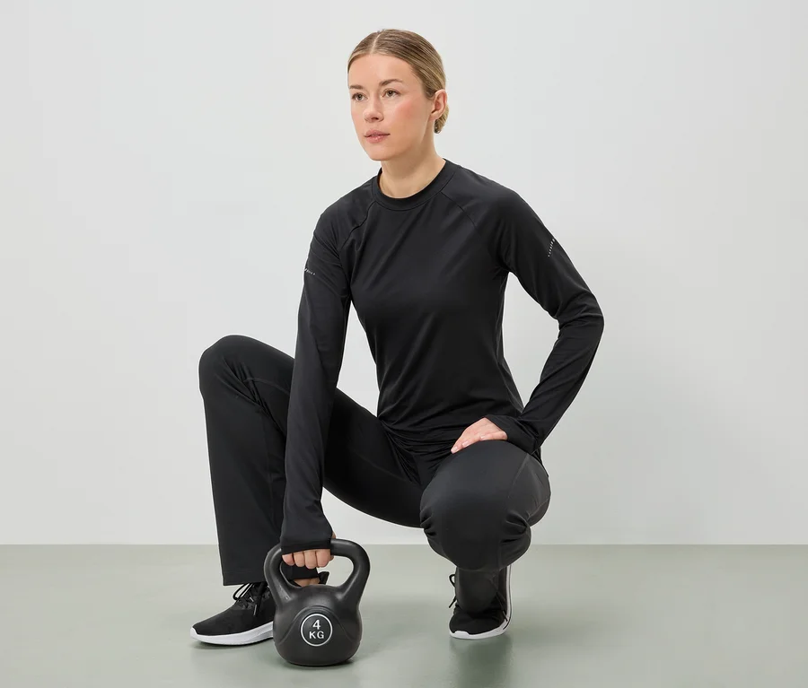 Fekete sportruházatot viselő nő guggol, és mindkét kezével egy 4 kg-os kettlebellt tart.