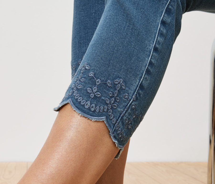 Közeli kép egy farmernadrágról, amelynek a szárán hímzett lyukak vannak.