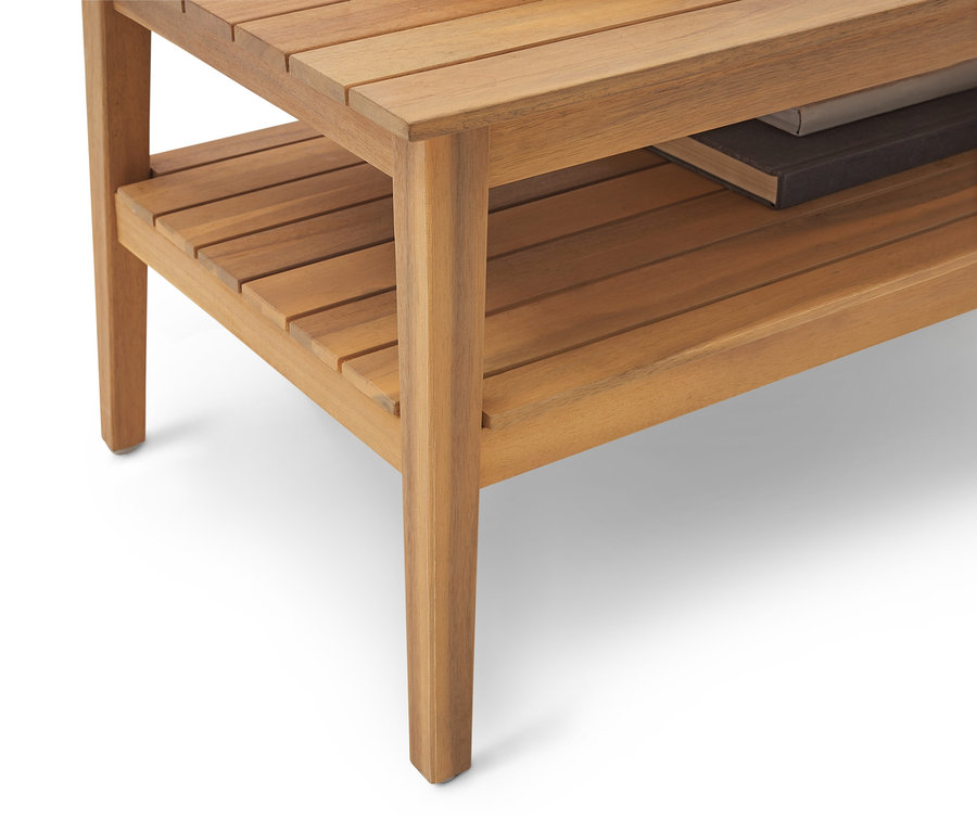 Közeli kép egy világosbarna fa lerakóasztalról polccal és egy könyvvel rajta.