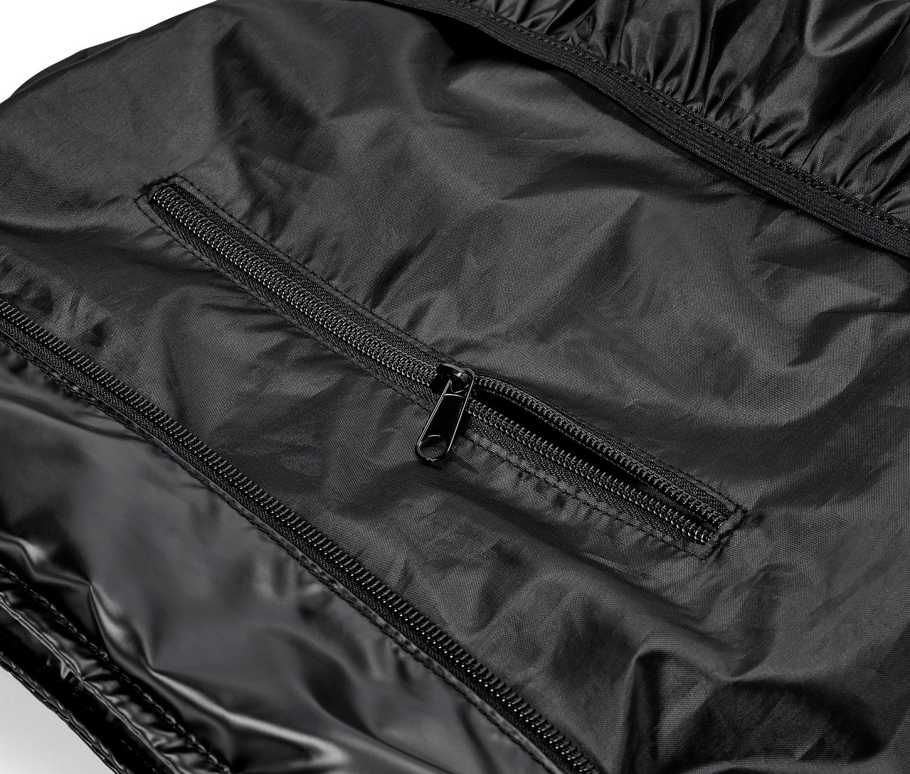 Fényes fekete ruhadarab részlete cipzárakkal.