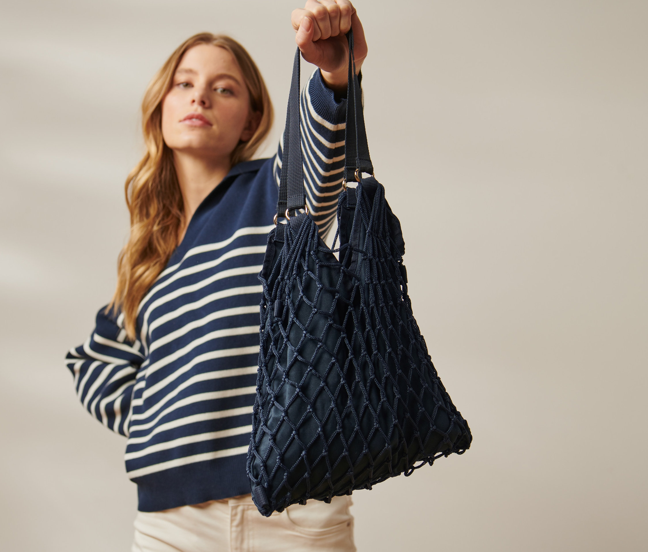 Szőke nő hálós táskát tart a feje fölé.