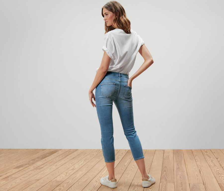 Nő pózol háttal a kamerának, 7/8-os treggings – Fit »Nelly« és fehér póló van rajta.