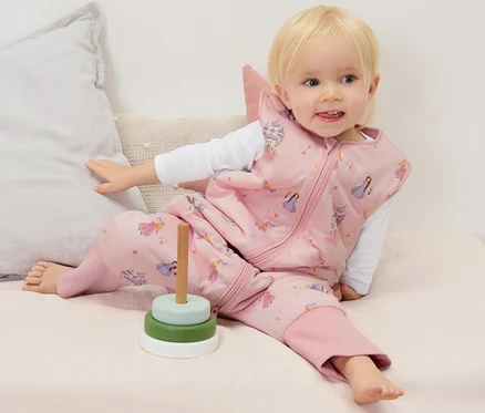 Kisgyermek ül a matracon és Hálózsák nadrágszárakkal, 2,5 TOG, kb. 90 cm terméket visel.