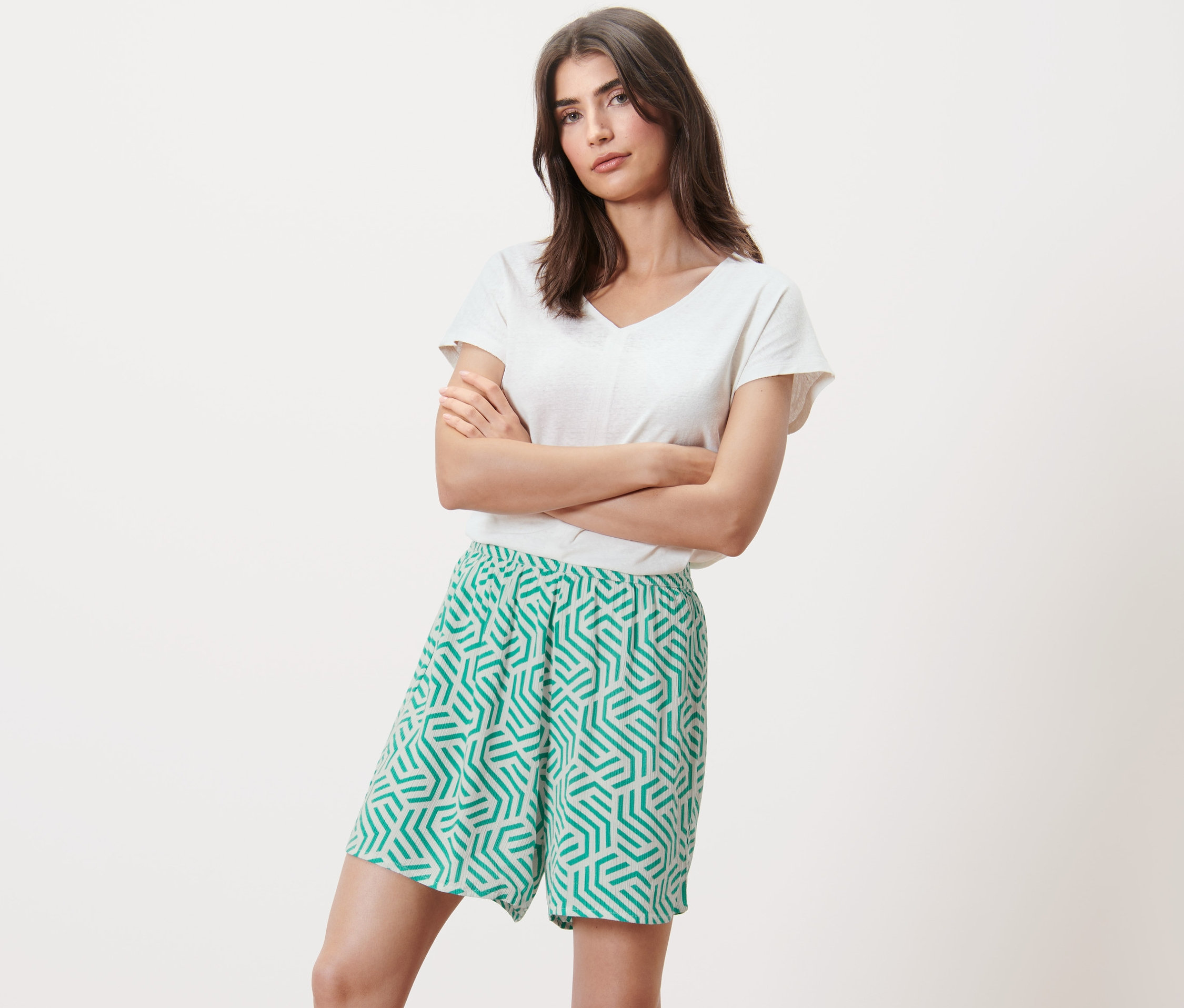 Nő pózol karba tett kézzel, mintás rövidnadrágban.