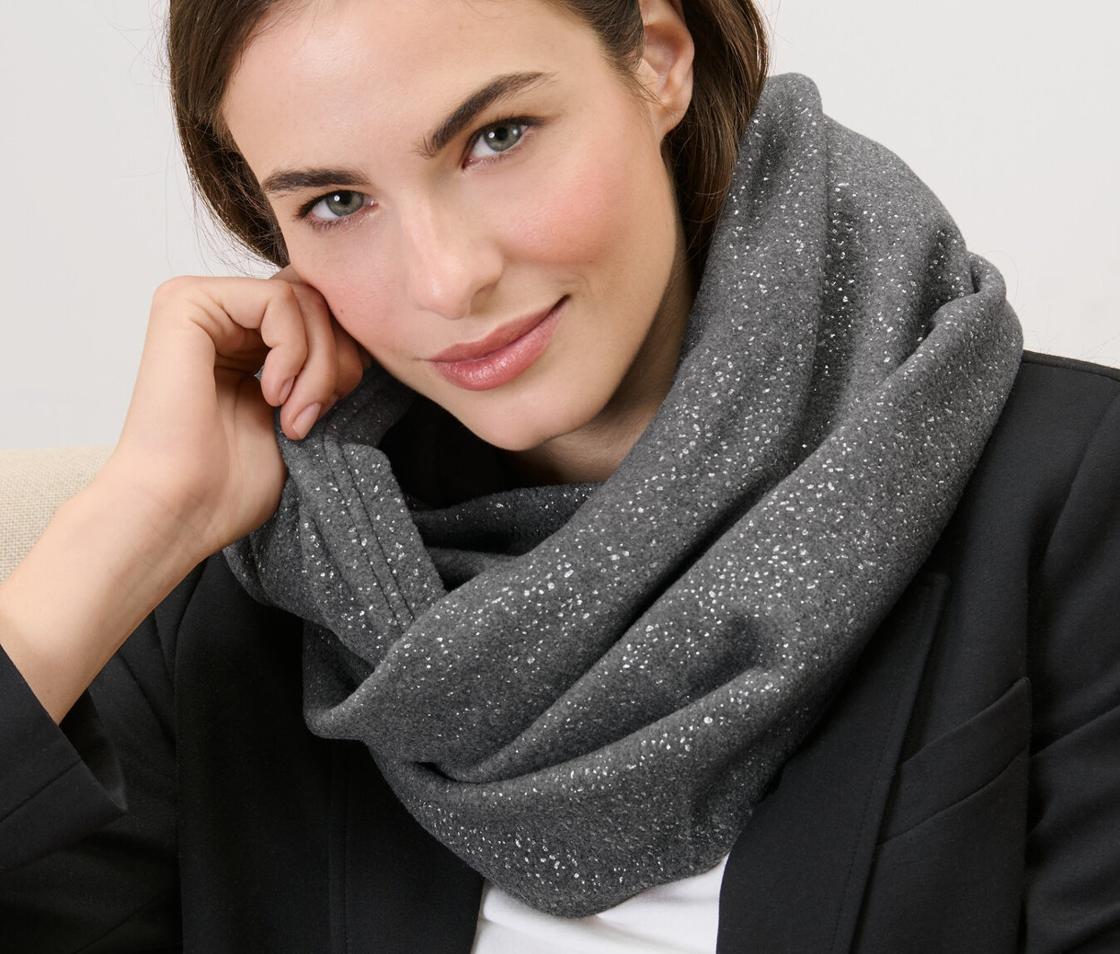 Egy nő ül, és egy szürke, csillogó női polár csősálat visel.