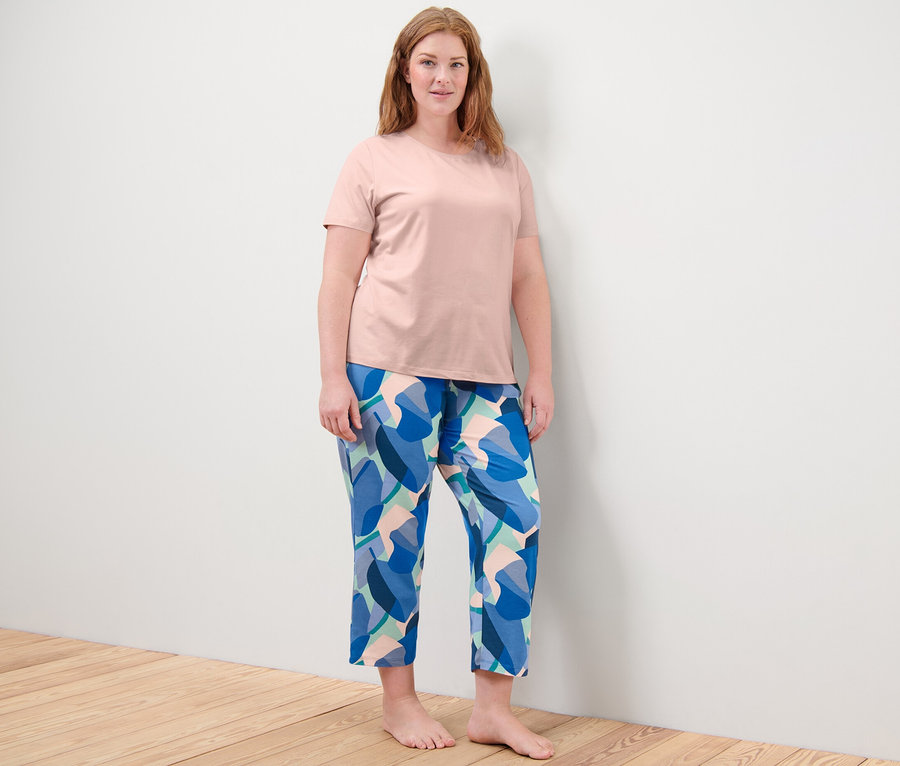Nő áll, mintás rózsaszín pizsamában.