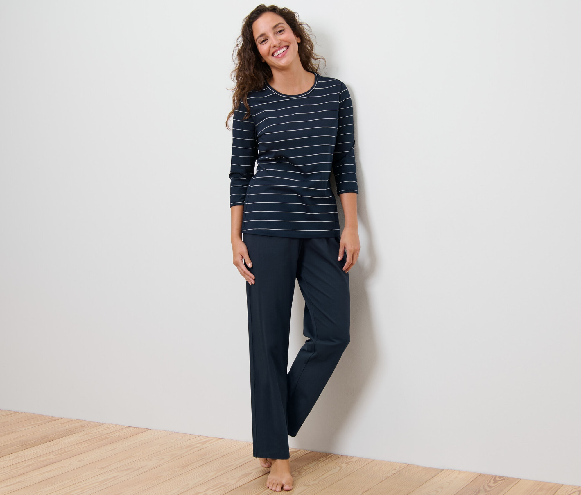 Egy nő áll és csíkos pizsamát visel.