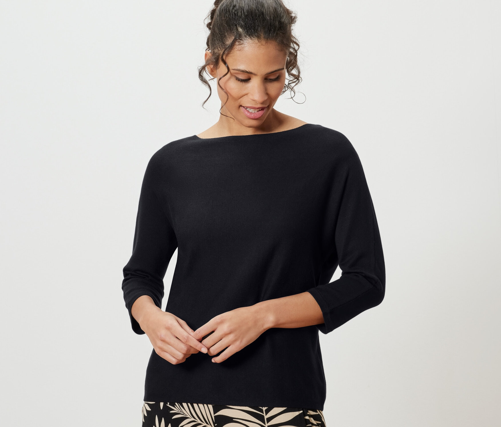 Nő visel fekete finom kötésű pulóvert.