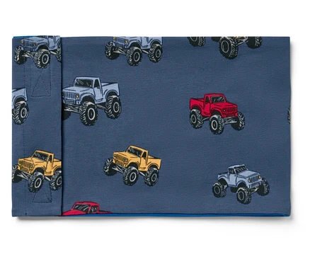 Szövet szürke, piros és sárga monster truck mintával, kék háttéren.
