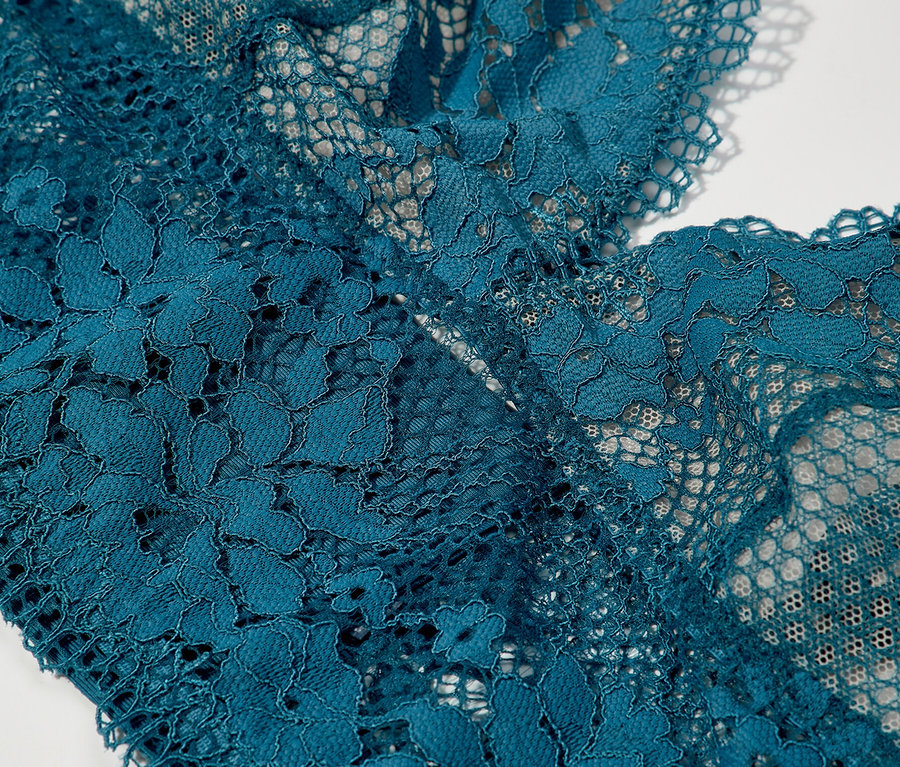 A Passionata merevítő nélküli, petrolkék »Nina« háromszög alakú melltartójának részlete virágos csipkével.