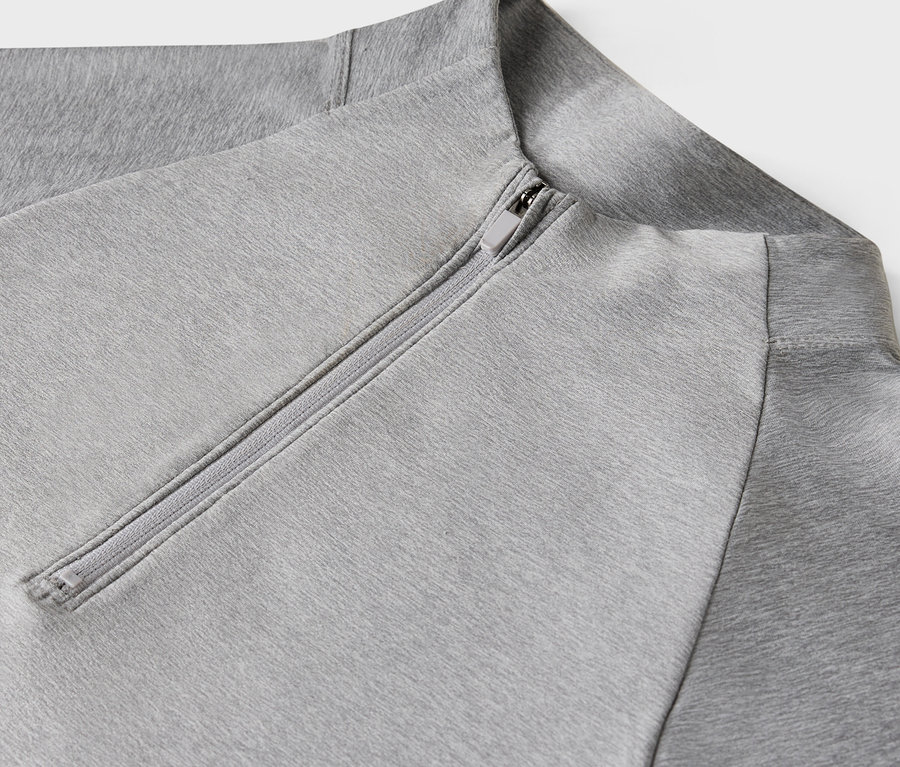 Egy világosszürke, cipzáros pulóver részlete.