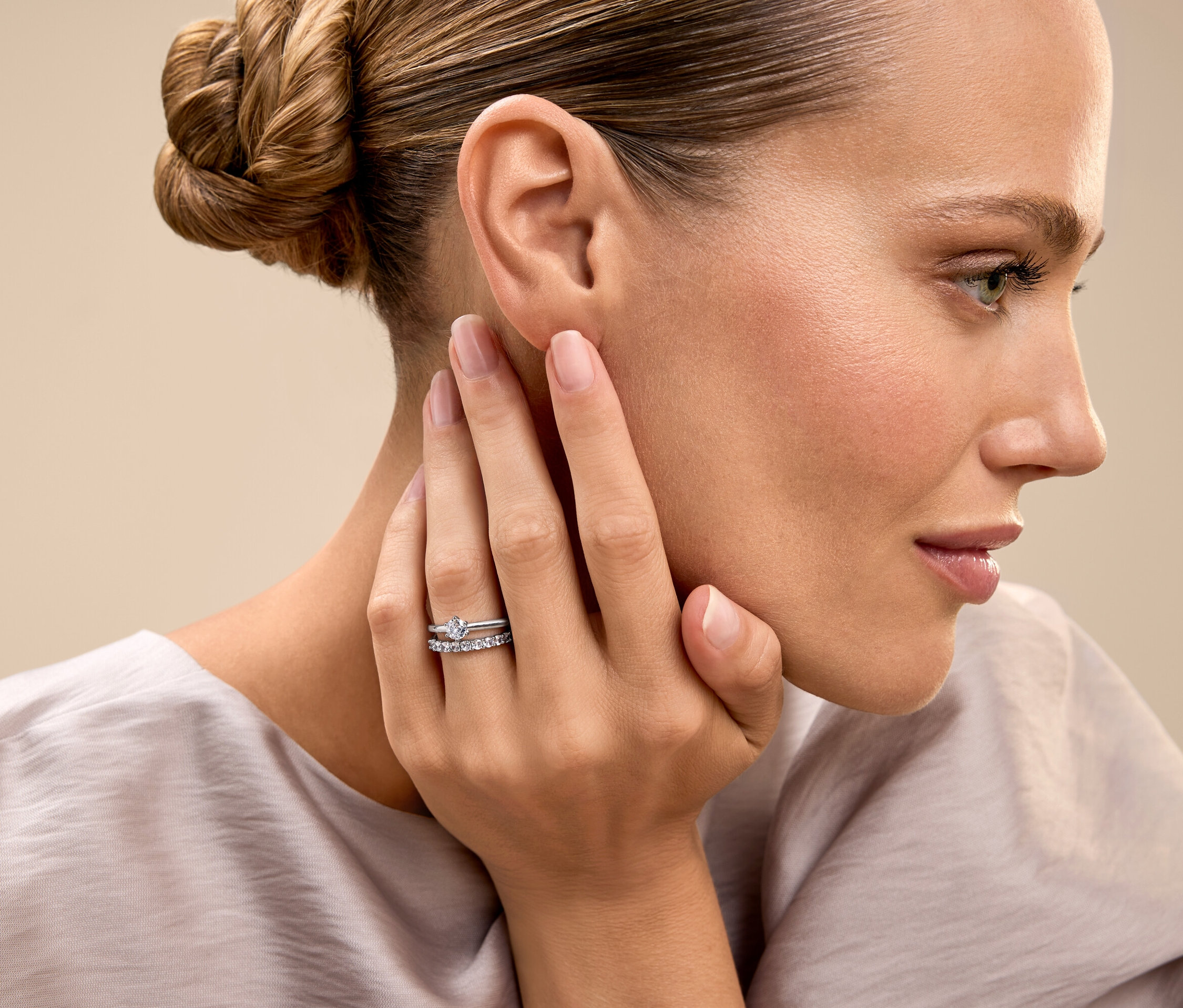 A feltűzött hajú nő megérinti az arcát, és egy gyűrűt mutat.