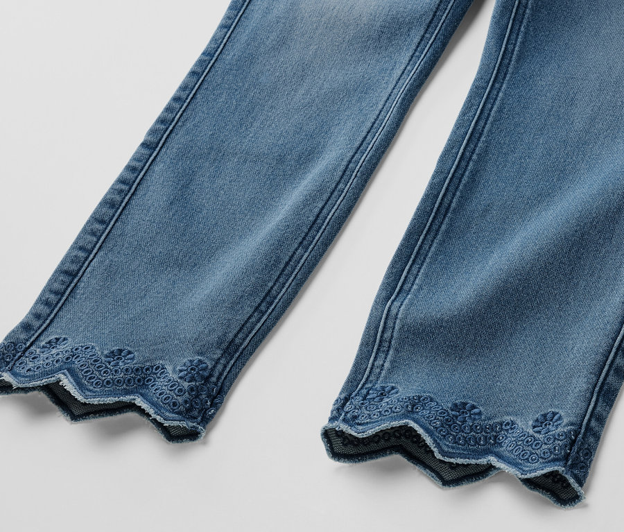 Két szár részlete világoskék, 7/8-os, lyukhímzéses treggingsből.