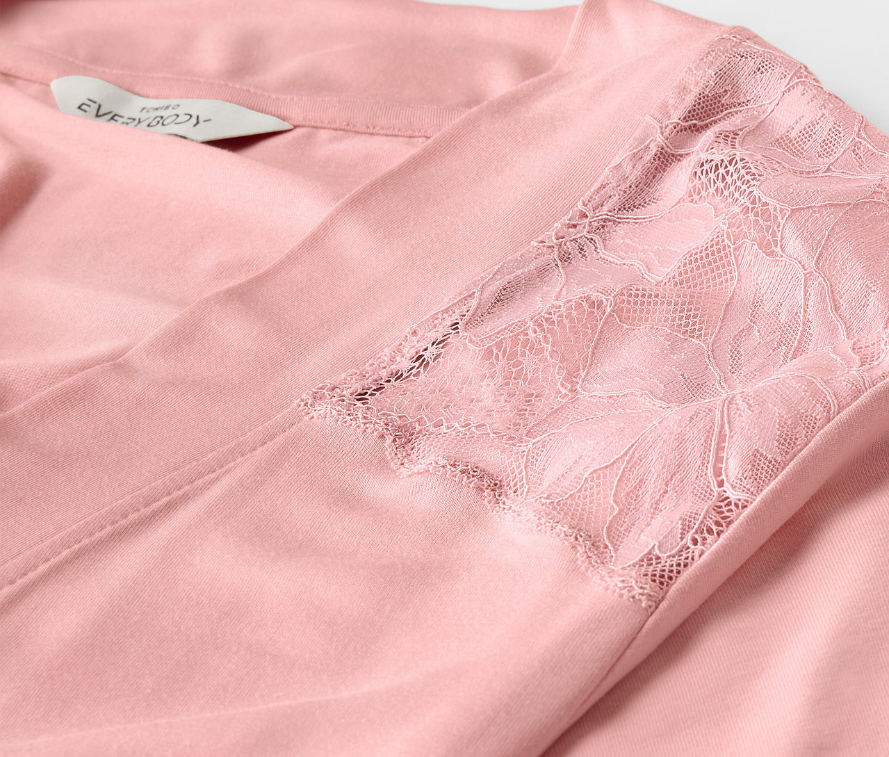 Egy rózsaszín köntös részlete csipkével az ujján.