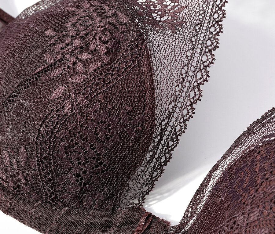 Egy sötétlila csipkés melltartó közeli képe fehér háttéren.