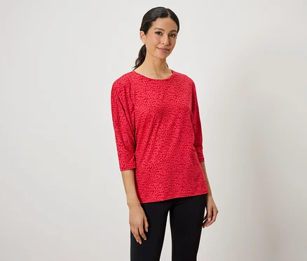 Nő visel egy vörös, állatmintás felsőt és fekete leggingset.