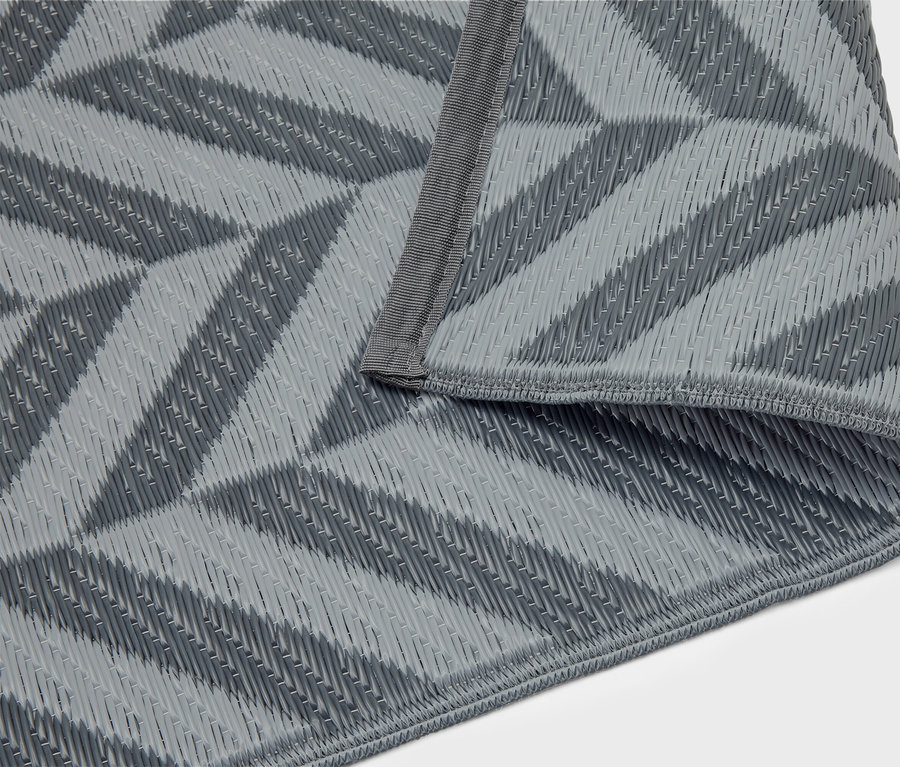 Egy szürke, geometrikus mintázatú pikniktakaró összehajtva fekszik egy fehér háttéren.