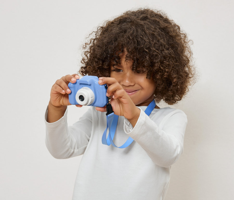 Göndör hajú gyermek kék játék fényképezőgépet tart.