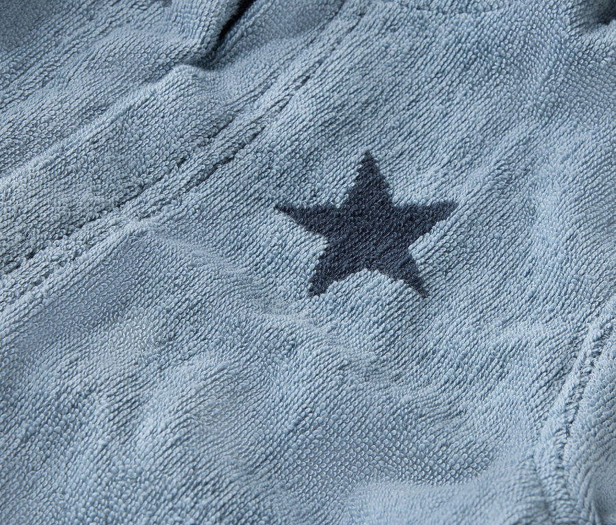 Egy világoskék fürdőköpeny közeli képe sötétkék csillagokkal.