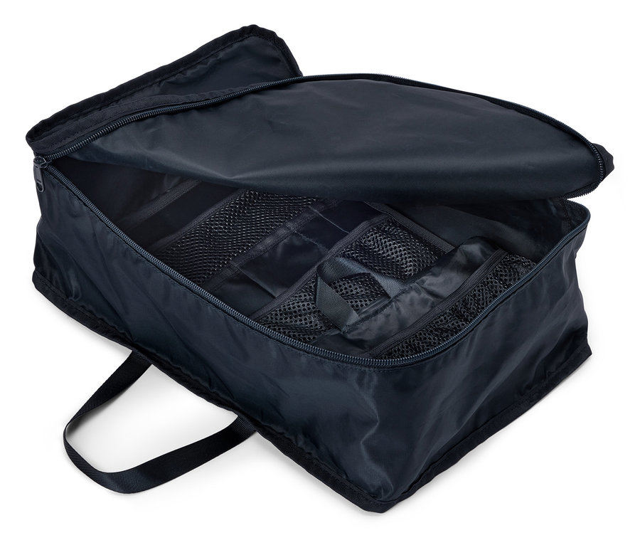 Kinyitott, tengerészkék utazótáska cipzárral és több rekesszel, felülnézetből.