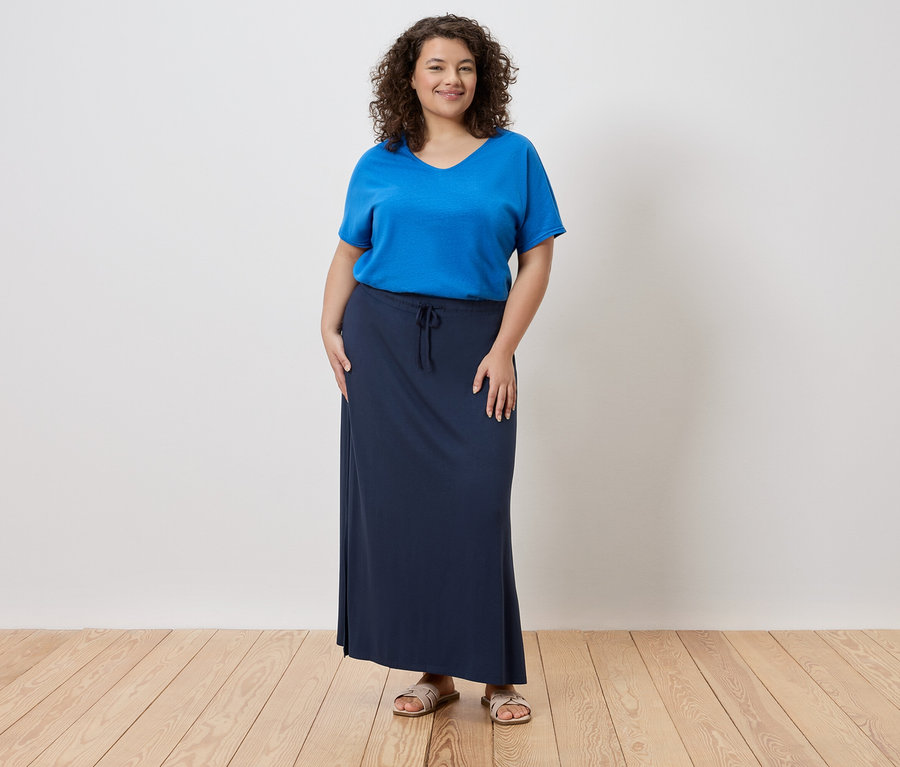 Nő kék pólót és hosszú, sötétkék szoknyát visel.